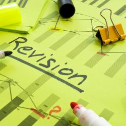 Revision materials scattered over a document with the word revision in bold and underlined